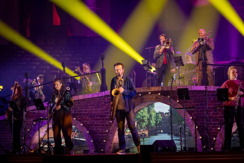 Een muzikale uitvoering met een band op een podium, omringd door kleurrijke verlichting en instrumenten.