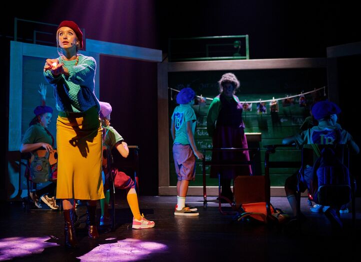 Theateroptreden met acteurs in kostuums op het podium, verlicht door sfeerverlichting, met verschillende achtergronden.