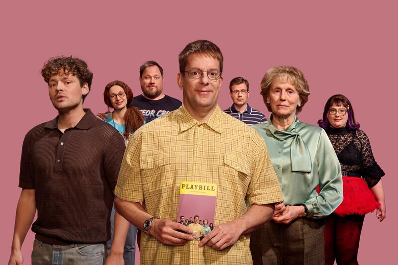 Groep mensen staat in een rij voor een roze achtergrond, met een man in het midden die een boek vasthoudt.