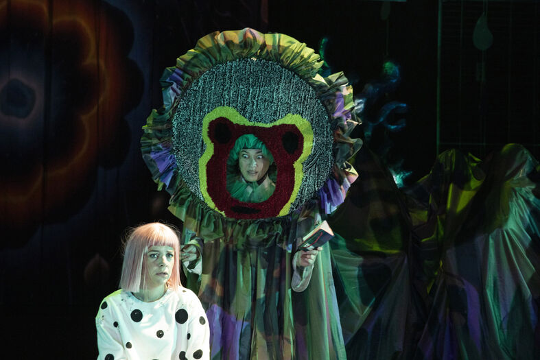 Twee acteurs in een theatrale voorstelling met kleurrijke kostuums en opvallende accessoires.