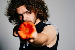 Flip Noorman met krullend haar richt een feloranje bloem scherp naar de camera.