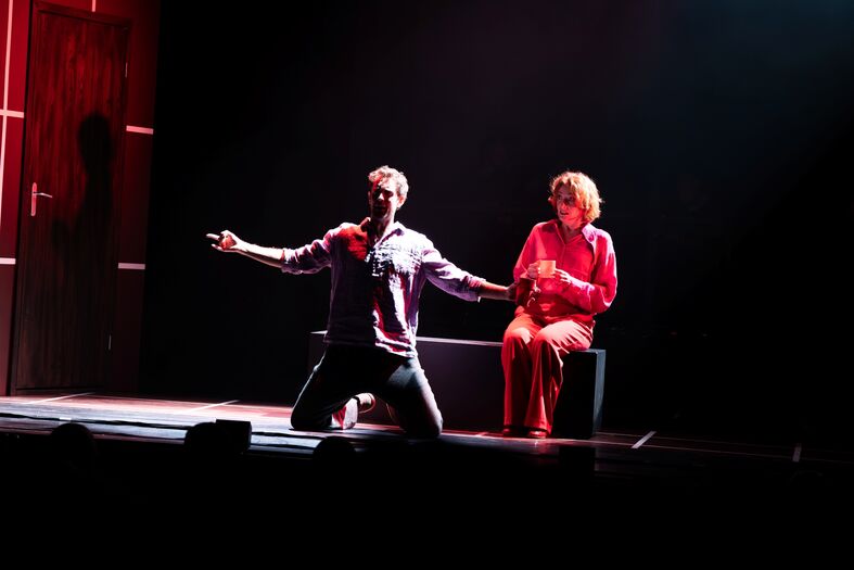 Acteurs op een podium tijdens een theatrale voorstelling, met spotlight en dramatische pose.