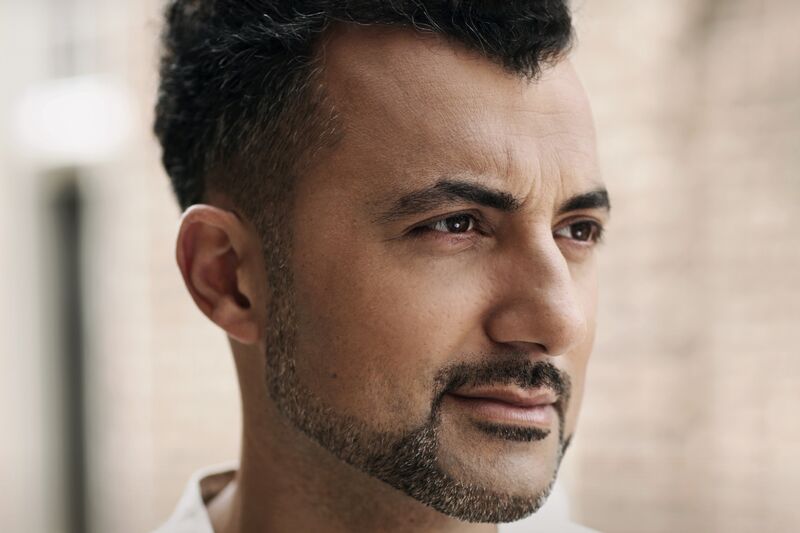 Portret van een man met een korte baard, kijkend naar de rechterzijde, met een neutrale achtergrond.