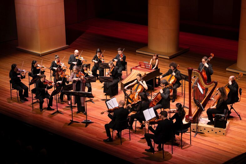 Een klassiek ensemble speelt op een podium met houten vloer, omringd door sfeervolle verlichting.