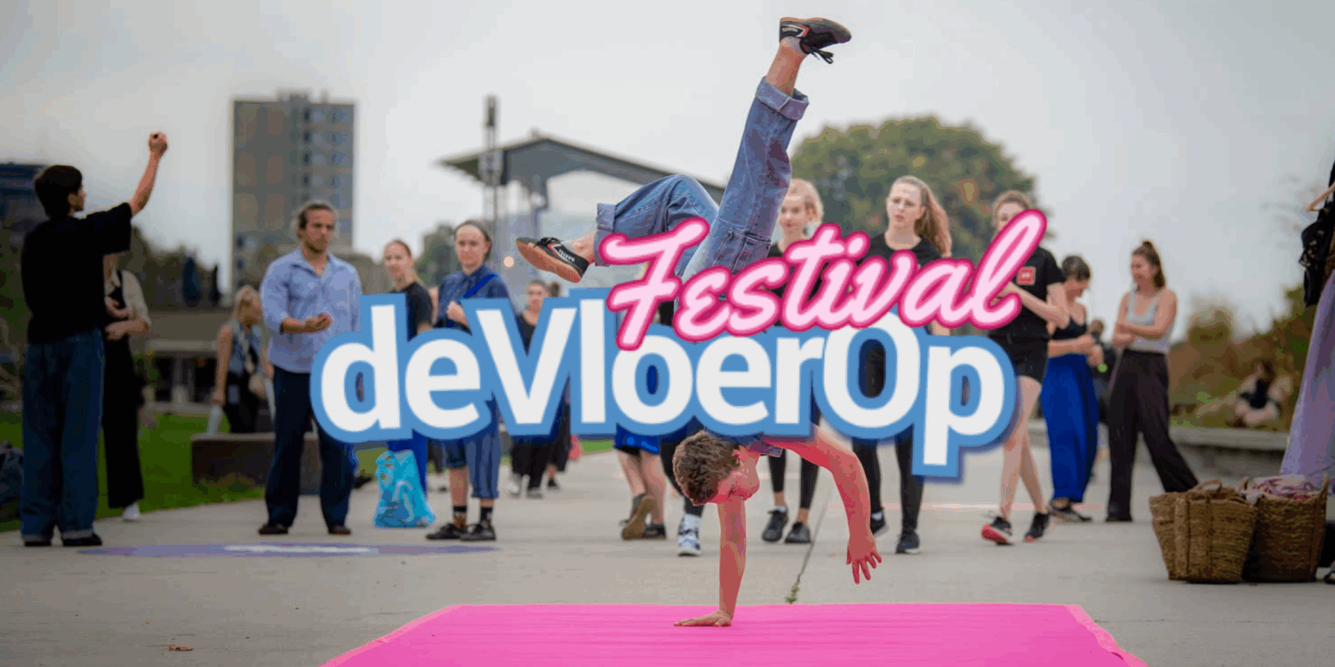 Een groep mensen op een festival, met iemand die een handstand doet op een roze mat. De naam van het festival is "Festival de Vloer Op".