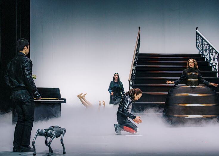 Theater voorstelling met acteurs op een mistige scène, een trap op de achtergrond en een hond op de voorgrond.