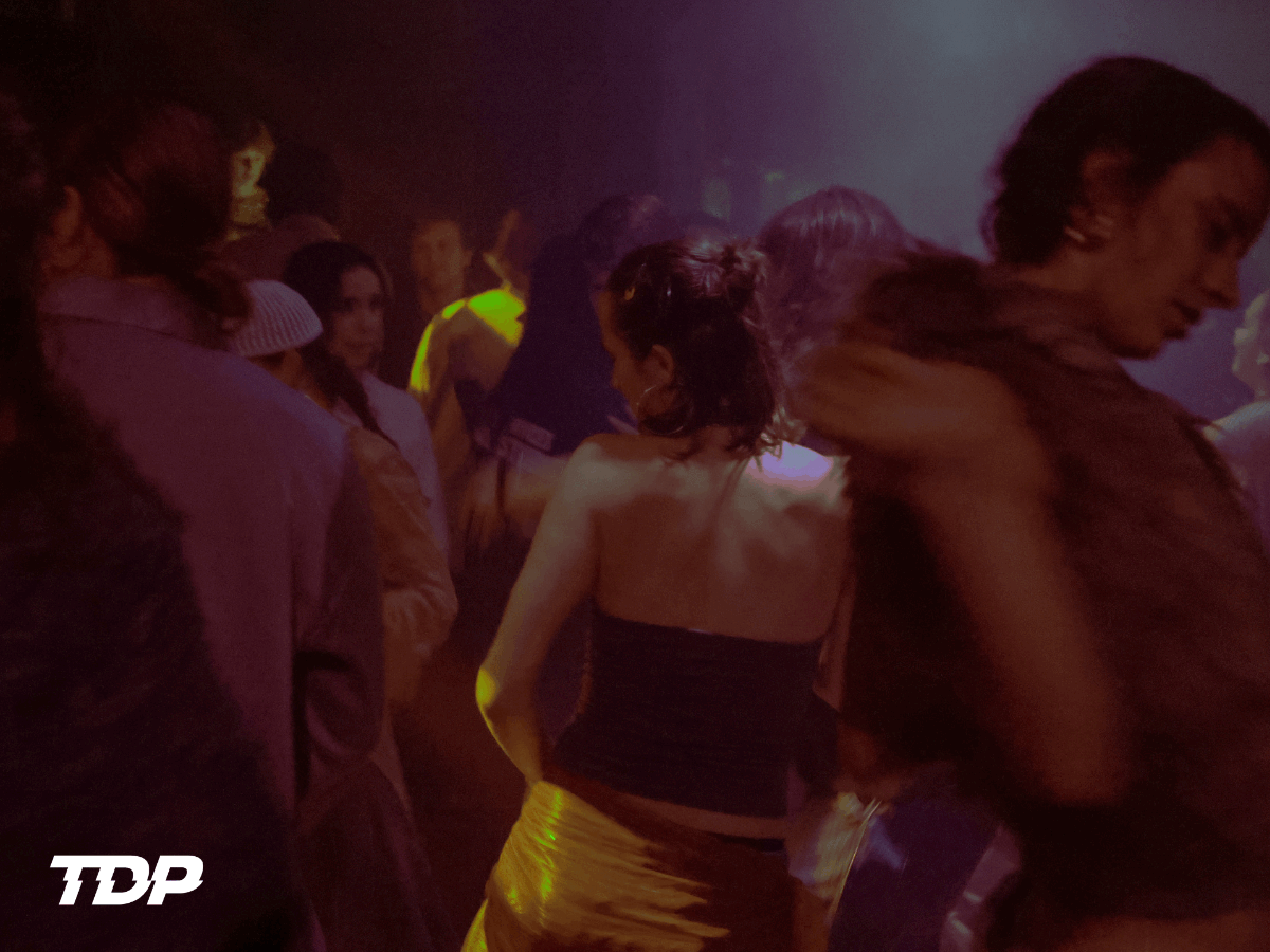 Groep mensen danst in een sfeervolle, verlichte nachtclub met rokerige atmosfeer.
