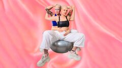 Twee personen met geschoren hoofden poseren zittend op een fitnessbal tegen roze achtergrond.