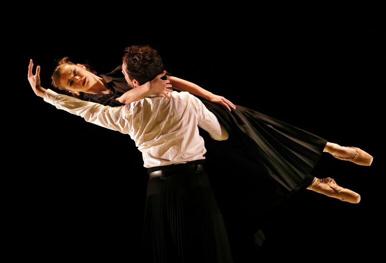 Danser tilt partner horizontaal terwijl zij sierlijk haar arm uitstrek.