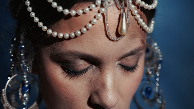 Portret van een vrouw met een subtiele uitstraling, versierd met een elegante haaraccessoire van parels en sapphieren.