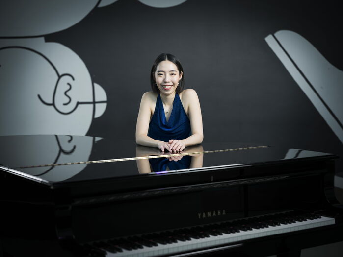 Vrouw in een blauwe jurk leunt op een zwarte piano met een vrolijke achtergrondtekening.