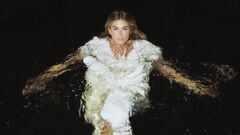 Roxanne Hazes in water in een witte jurk met een donkere achtergrond.