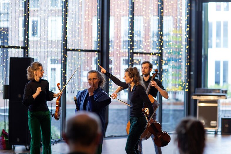 Muzikanten voeren een live optreden uit in een lichte ruimte met grote ramen en decoraties.