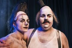 Een man met een snor en een vrouw met een punkachtige uitstraling, beiden met theatrale make-up, poseren samen op het podium.