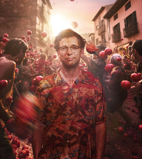 Pieter Derks in een Hawaï shit in een straat vol mensen die met tomaten gooien.