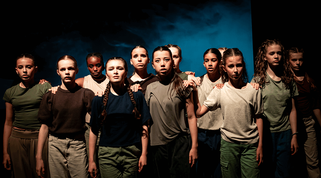 Groep van tien dansers in een donkere ruimte, met intense gezichten en een blauwe achtergrond, allen in casual kleding.