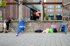 Groep jongeren aan het oefenen met parkour, waarbij ze over een muur klimmen en zich aanpassen aan hun omgeving.
