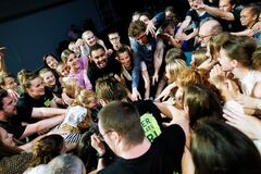 Groep mensen verzameld rondom een centrale figuur, met enthousiasme en interactie in een levendige omgeving.