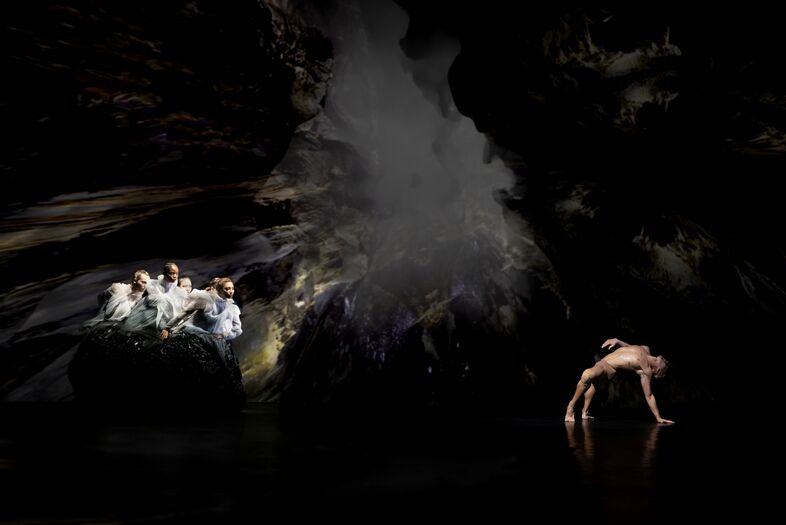 Een silhouet van een danser in water, omringd door abstracte vormen en een spetterende waterdruppel.