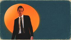 Man in een zwart pak staat voor een grote oranje cirkel, met een blauwe achtergrond.