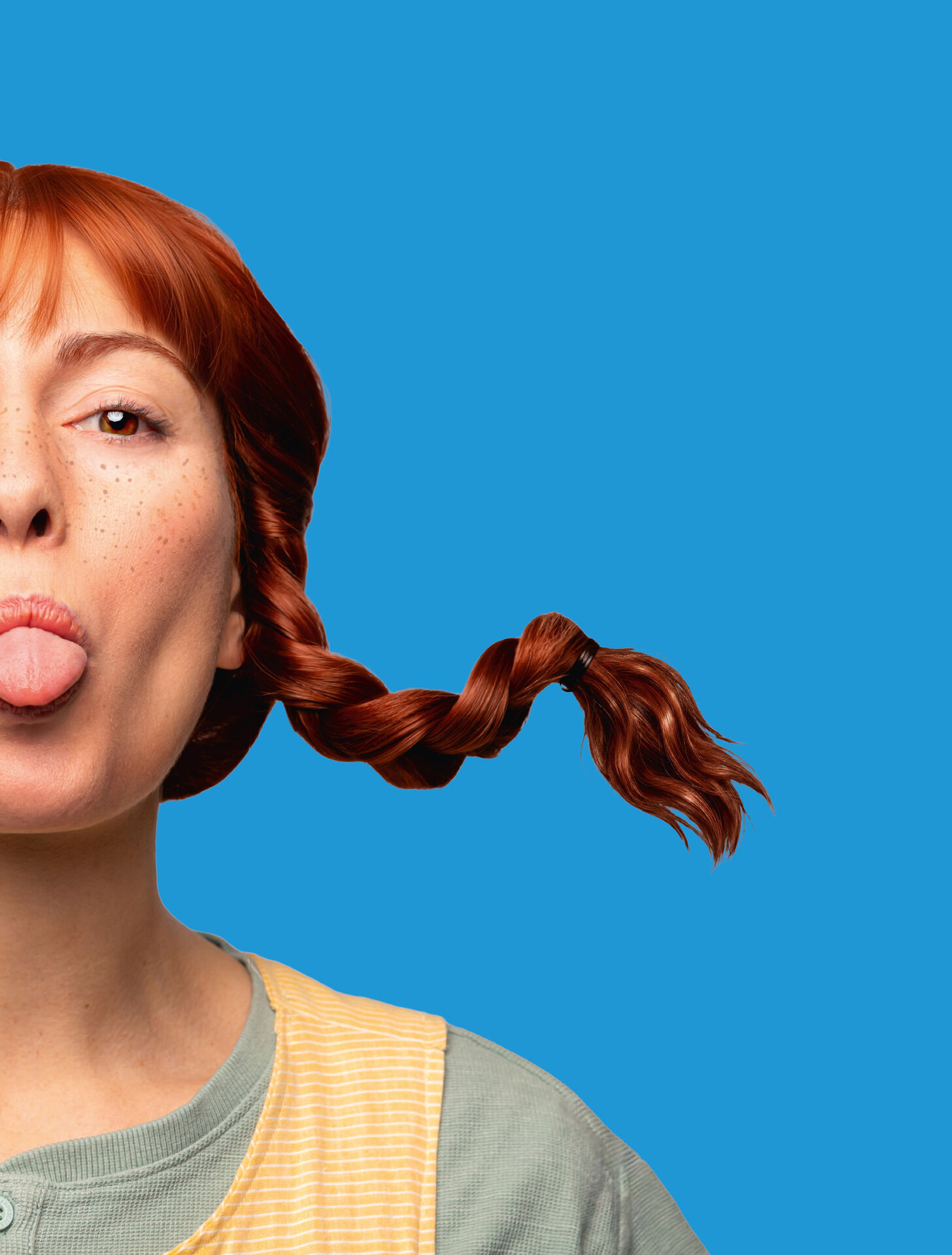 Vrouw met een speelse uitstraling steekt haar tong uit en heeft een gevlochten staart, tegen een blauwe achtergrond.