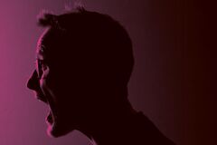 Zijprofiel van een persoon die met wijd open mond schreeuwt, belicht in roze en donkerrood tegen een donkere achtergrond.